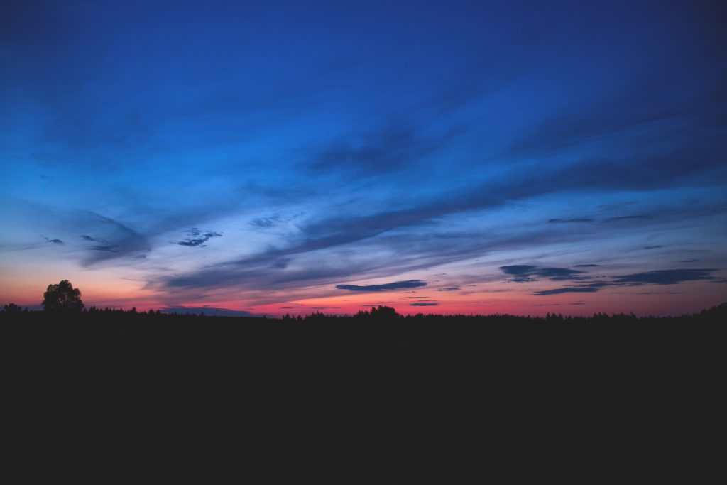 Dusk's setting sun lights up clouds to a bright peach Stock Photo