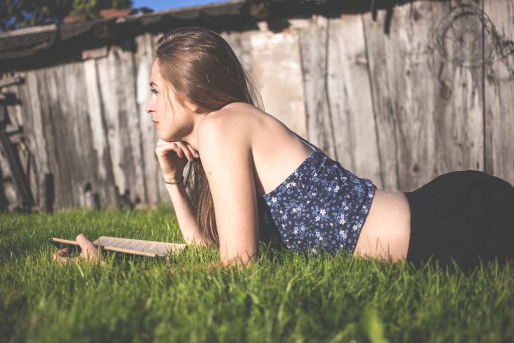 Pensive girl laying on grass - free stock photo