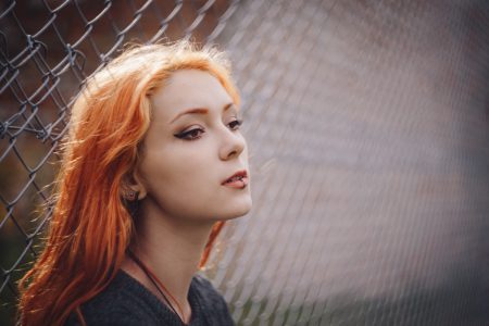 Girl leaning against a net fence - free stock photo