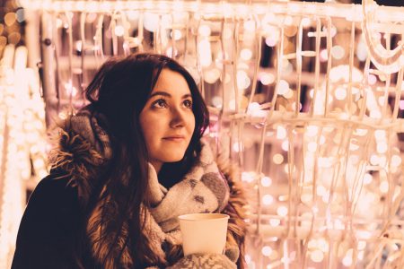 Christmas lights and a girl holding a coffee - free stock photo