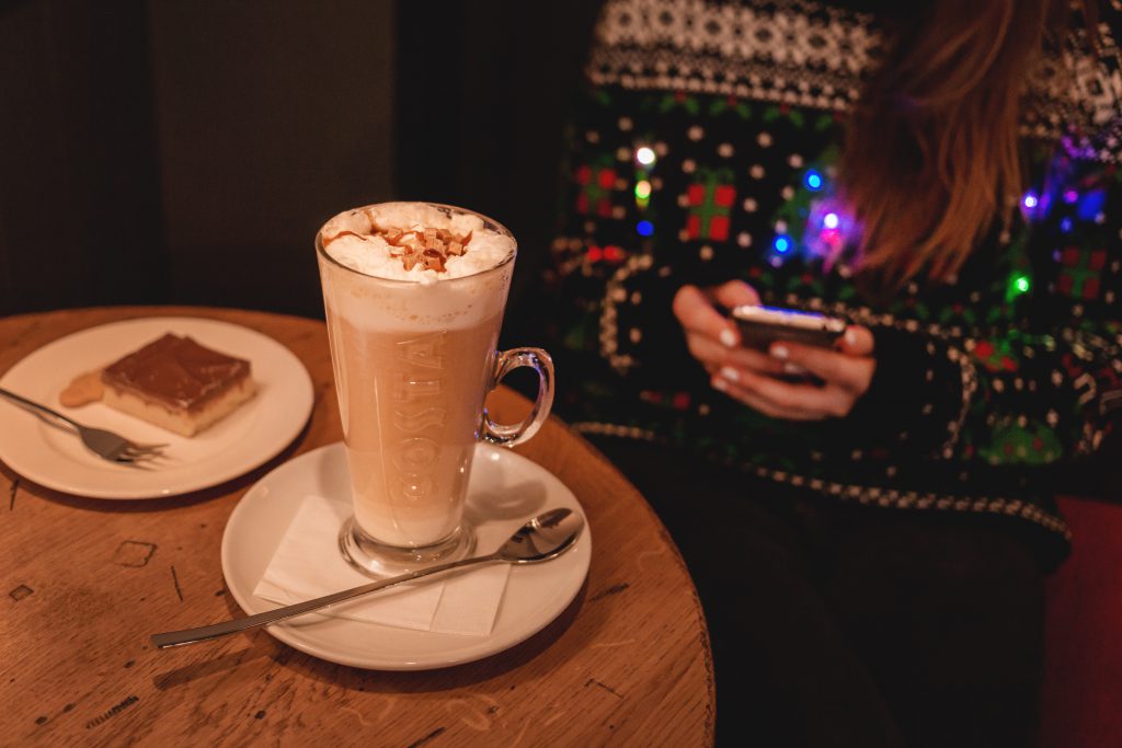 Girl in Christmas sweater sitting in a cafe - free stock photo