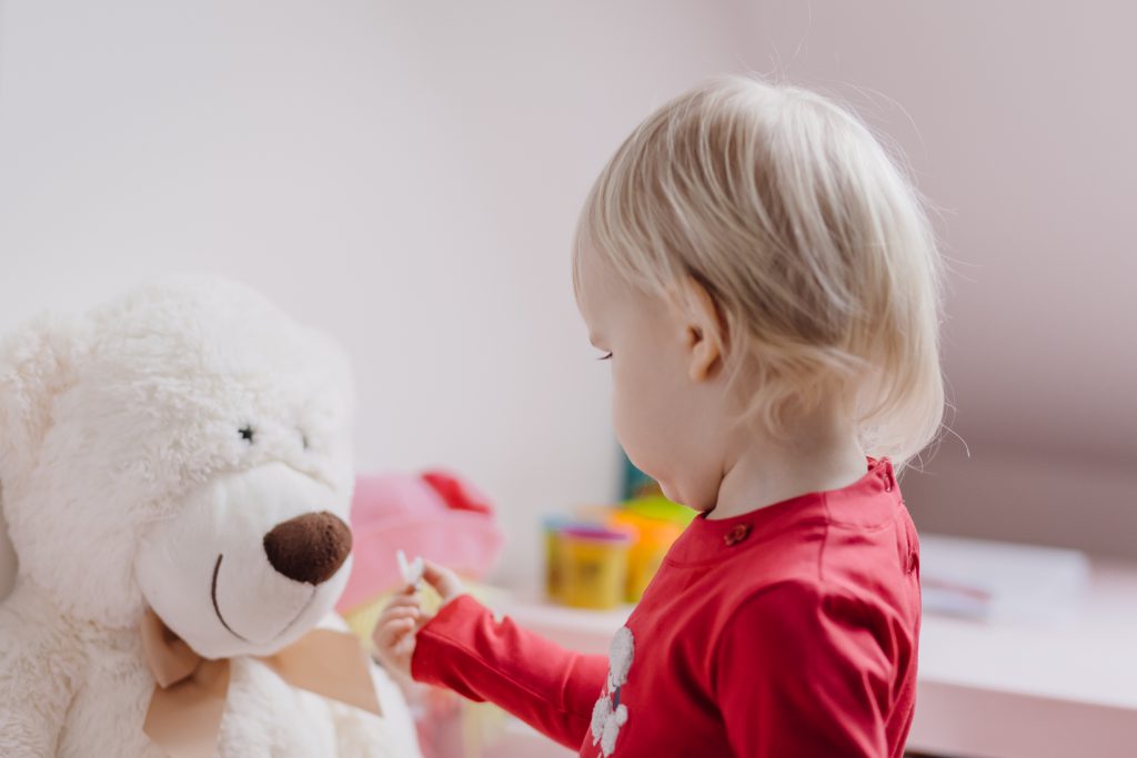 A little girl feeding her teddy - free stock photo