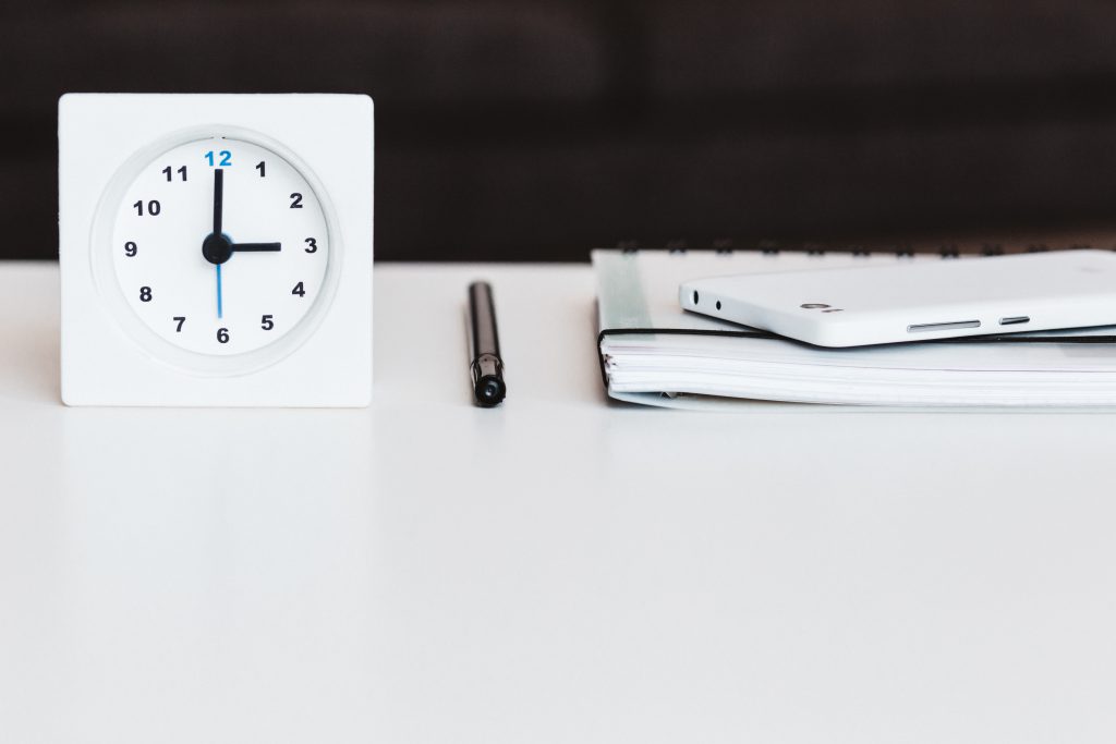 A table clock, a planner and a phone - free stock photo