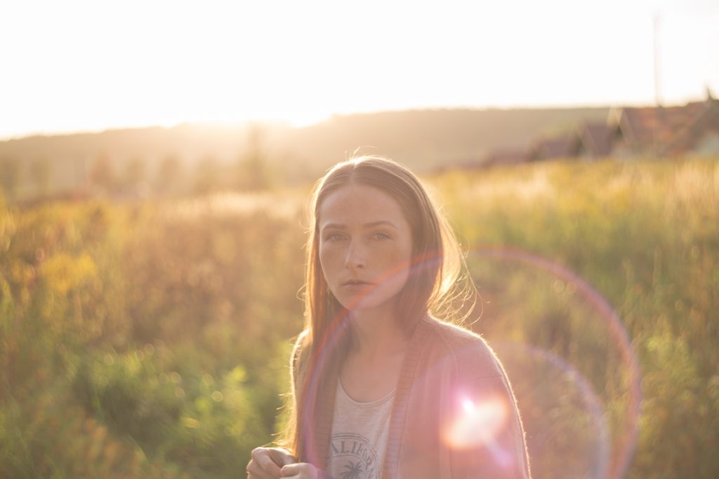 A girl in the meadow with sunflare - free stock photo