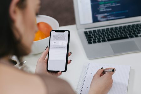 Female holding an iPhone X and taking notes - free stock photo
