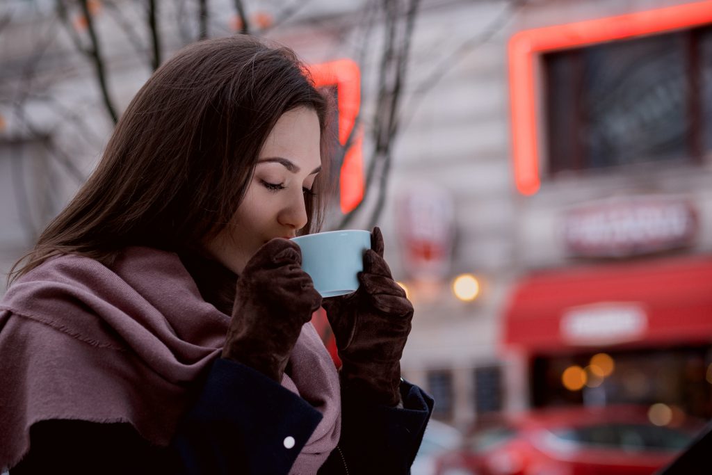 A woman drinking coffee outdoors - free stock photo