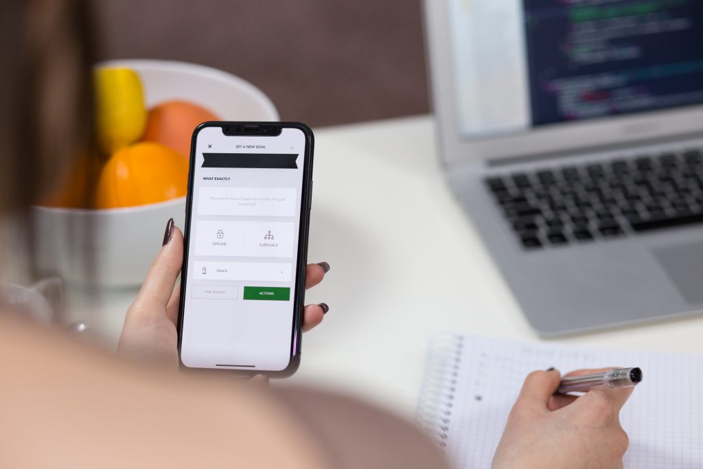 A female holding an iPhone X and taking notes 2 - free stock photo