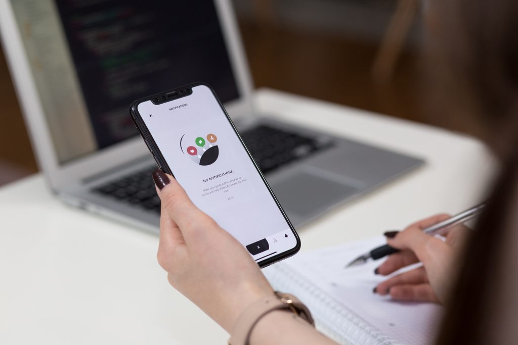 A female holding an iPhone X and taking notes 3 - free stock photo