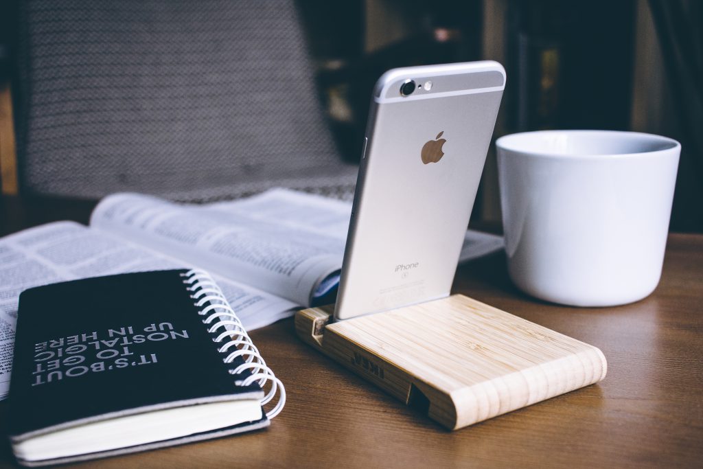 iPhone in a wooden phone holder - free stock photo