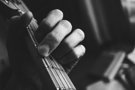 Guitarist hand playing guitar in black and white - free stock photo