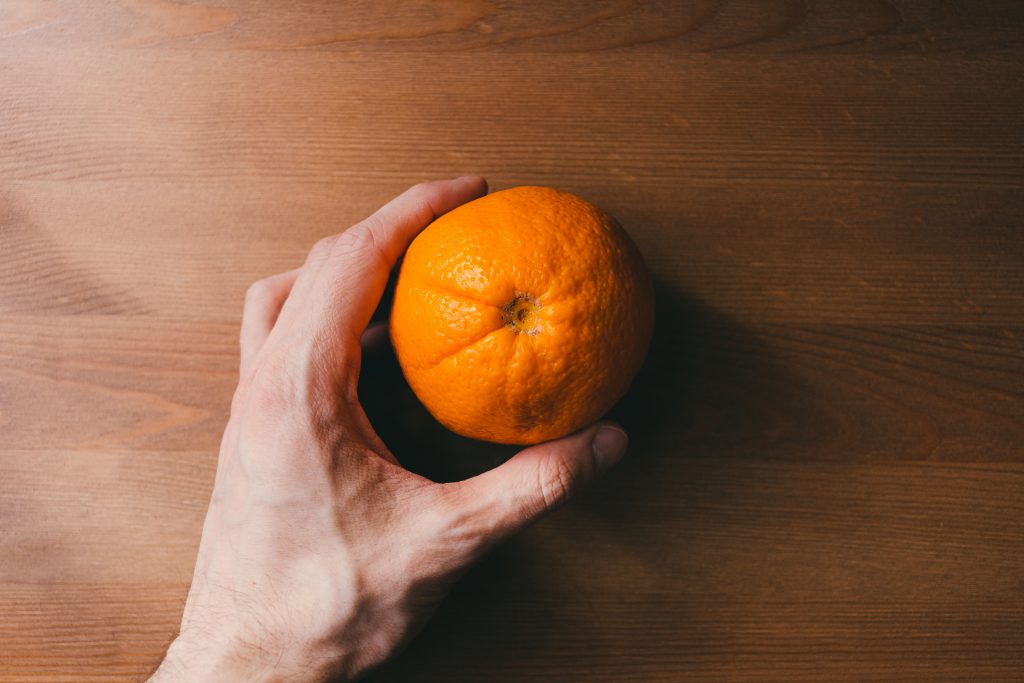 Orange in a male hand - free stock photo