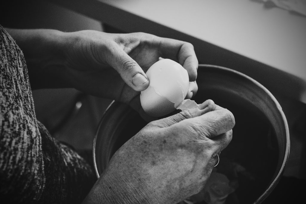 Old woman peeling an egg - free stock photo