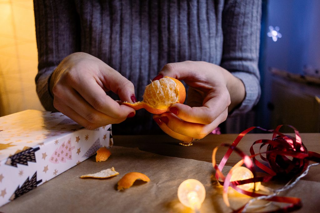 A female peeling a mandarin in a festive setting - free stock photo