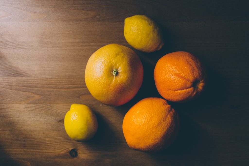 A grapefruit, oranges and lemons on a wooden table - free stock photo