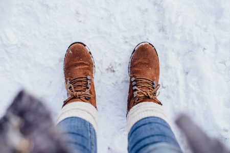 Female feet standing on a snow-covered pavement - free stock photo