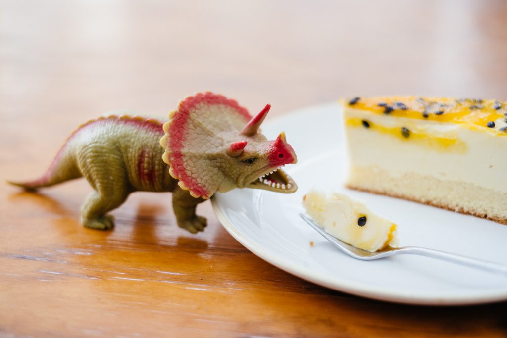 Rubber toy dinosaur about to eat a cake 2 - free stock photo