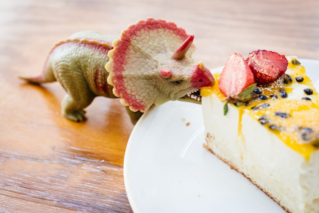 Rubber toy dinosaur about to eat a cake 3 - free stock photo