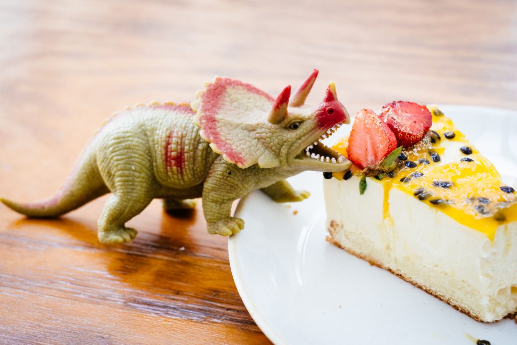 rubber_toy_dinosaur_about_to_eat_a_strawberry_on_a_cake-1024x683.jpg