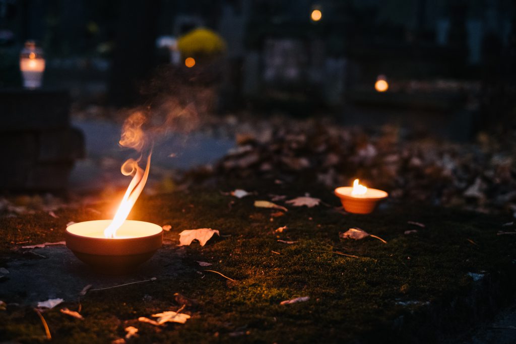 Burning candles on an old grave at the cemetery - free stock photo