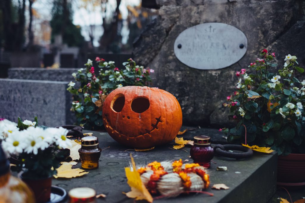 A carved pumpkin on an old grave at the cemetery - free stock photo