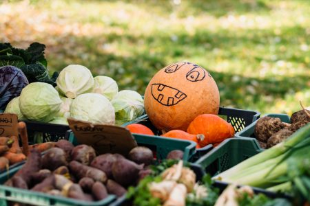 Pumpkin with a drawn face at an outdoors vegetable market - free stock photo