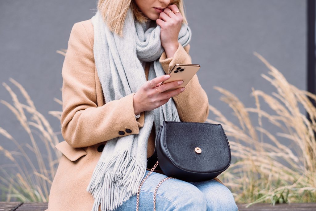 A female holding her phone looking worried on an autumn day 2 - free stock photo