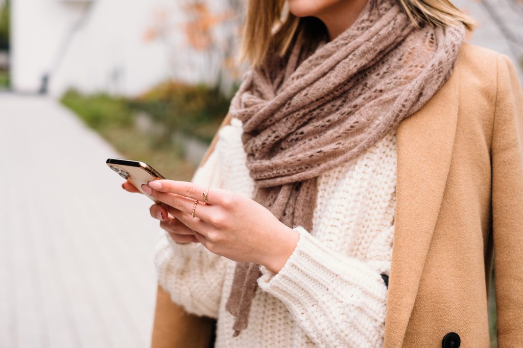 female_holding_her_phone_on_an_autumn_da