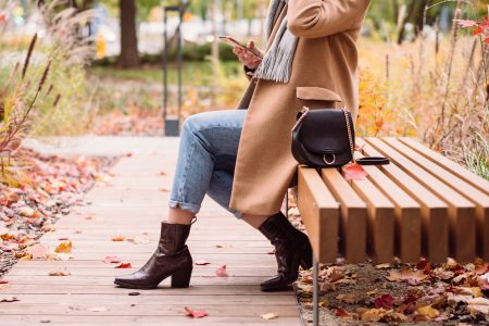 Female sitting on a bench and using her phone on an autumn day 4 - free stock photo