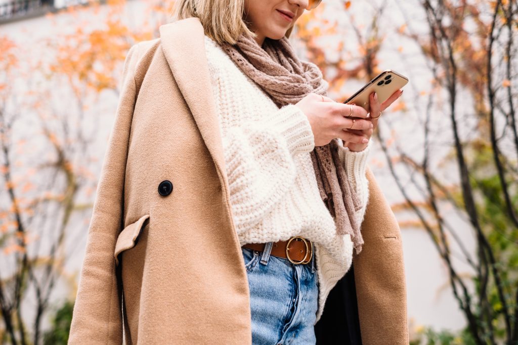 Smiling female holding her phone on an autumn day closeup 3 - free stock photo