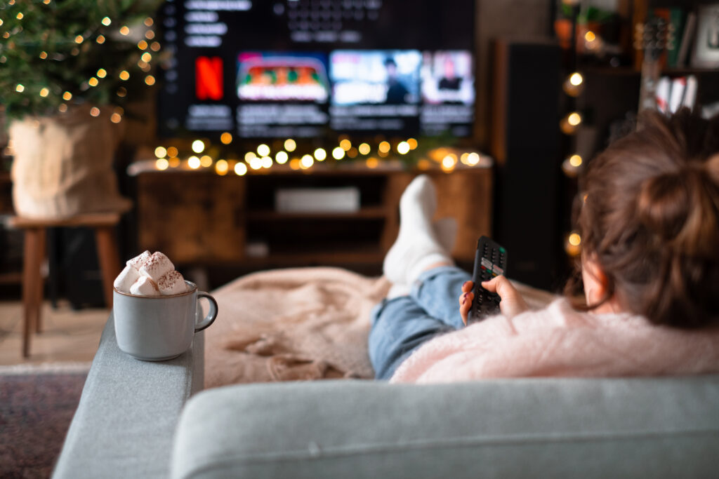 Female sitting on a sofa holding a remote control on Christmas - free stock photo