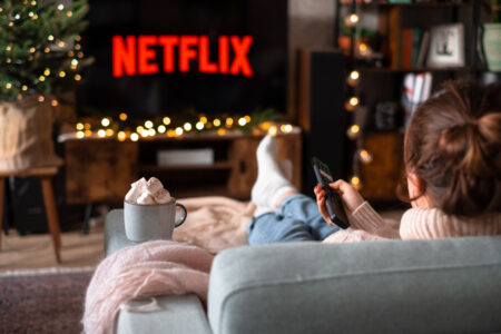 Female sitting on a sofa holding a remote control on Christmas 2 - free stock photo