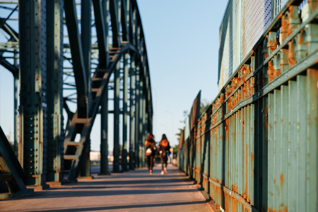 Two females walking across a rusty industrial overpass 3 - free stock photo