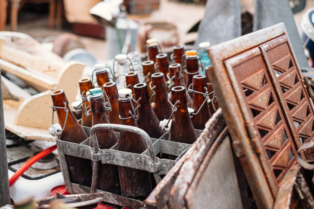 Old vintage brown glass bottles in a rusty metal crate at a flea market - free stock photo